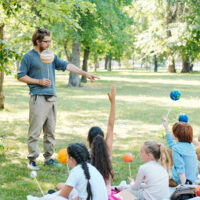 Hipster young astronomy teacher in glasses pointing at pupil while asking him about planets at outdoor class